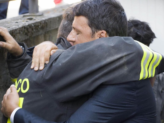 Amatrice &#8211; eine Stadt liegt in T...ngschef Renzi umarmt einen der Helfer.  | Foto: dpa