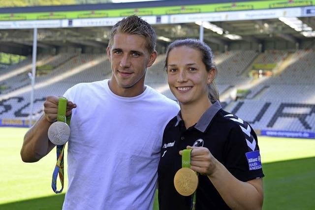 Nils Petersen und Laura Benkarth zeigen ihre Medaillen vor
