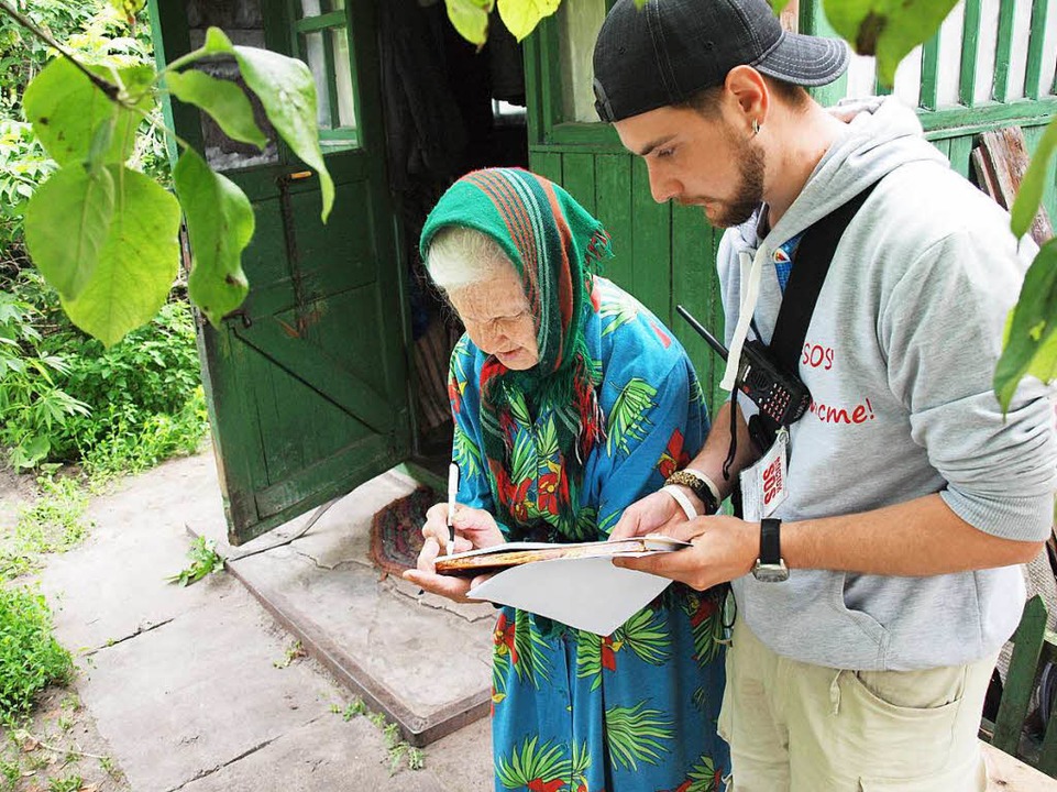 Ein Helfer bringt einer Greisin Medikamente.  | Foto: Rehman