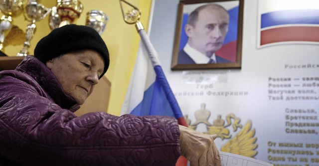 Eine Moskauerin whlt unter dem Portrt des Prsidenten.  | Foto: dpa