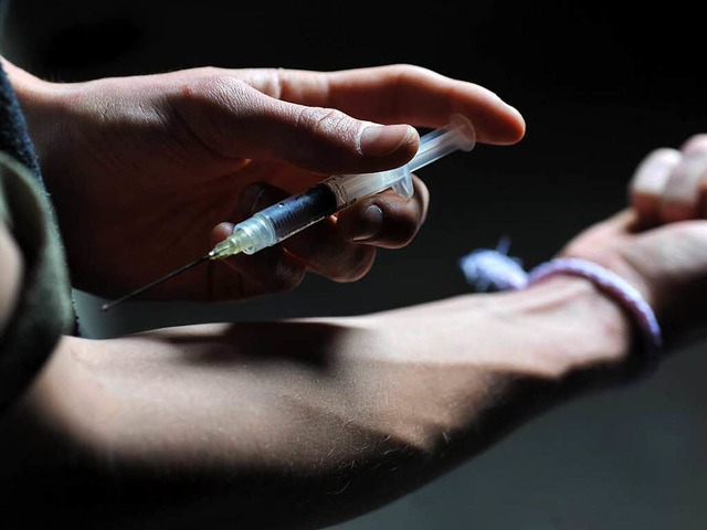 Ein Mann hlt eine Heroinspritze an se...r Drogensucht an schweren Krankheiten.  | Foto: dpa