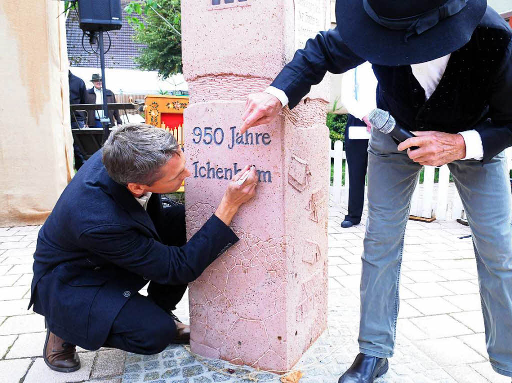 Ortsvorsteher Ralf Wollenbr (links)  bringt das i-Tpfelchen auf dem „Ichenheim“ an auf der Skulptur von Walter Henninger (rechts) an.