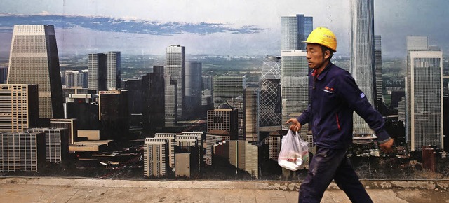 Ein Bauarbeiter in Peking luft an ein...vorbei, das moderne Zeiten ankndigt.   | Foto: dpa