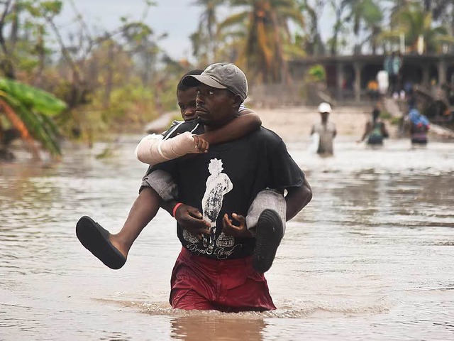 Ein Mann trgt seinen Sohn durch die F...em Hurrikan regnet es in Haiti weiter.  | Foto: AFP