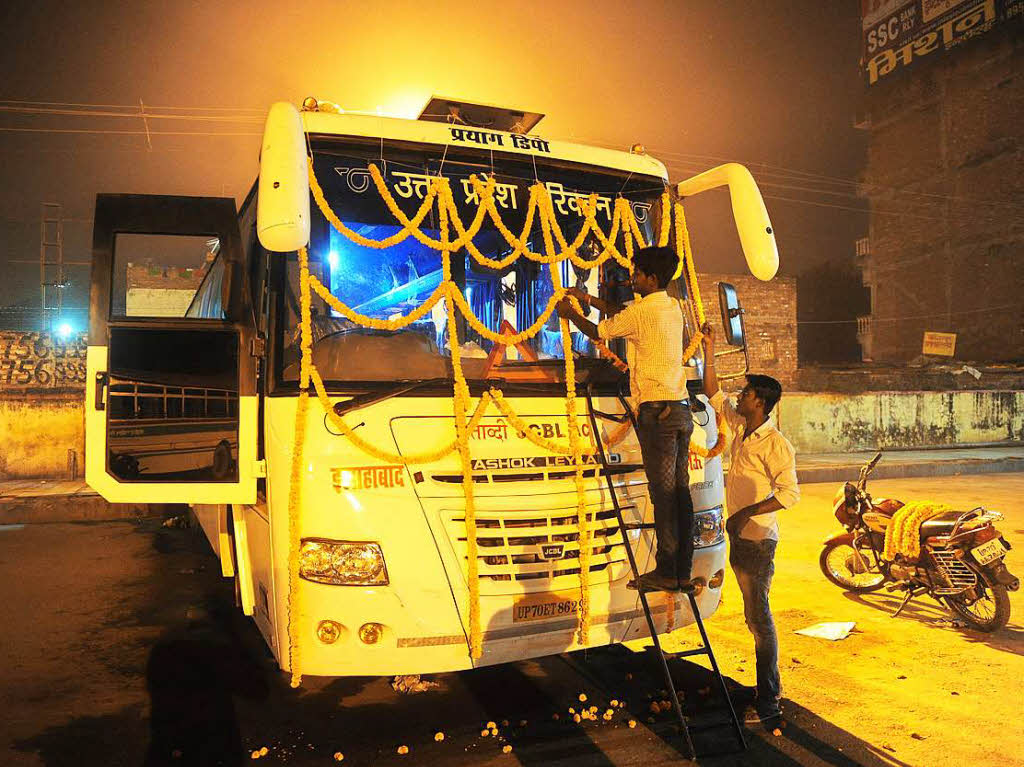 Ein indischer Busfahrer schmckt zu Diwali seinen Bus mit Girlanden.