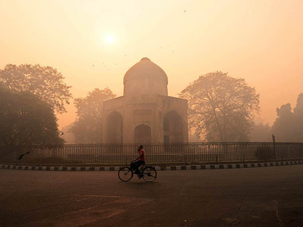 Ein indischer Fahrradfahrer fhrt am Tag nach dem Diwali-Festival an einem Monument in Neu-Delhi vorbei. Der Smog, der durch das Feuerwerk entsteht, ist ein Problem fr die Umwelt.