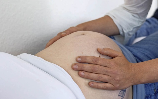 Eine Hebamme untersucht den Bauch einer werdenden Mutter.   | Foto: dpa