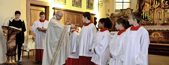 Sasbach. Pfarrer Schneider hngt den n...istranten die Ministrantenplakette um.  | Foto: Roland Vitt