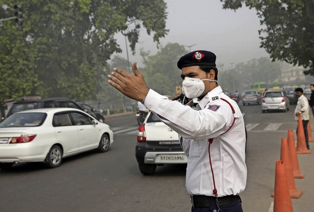 Ein Polizist mit Atemmaske regelt in Neu-Delhi den Verkehr.   | Foto: DPA