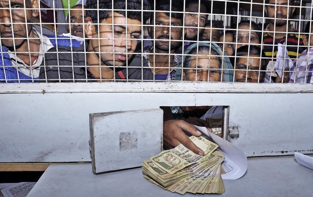 Menschen drngen sich im nordindischen...ltig gewordene  Scheine zu tauschen.   | Foto: dpa