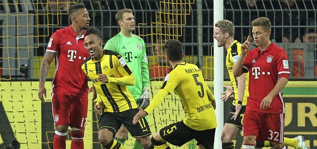Die Dortmunder bejubeln das Siegtor vo...die Bayern-Kicker schauen bedrppelt.   | Foto: dpa