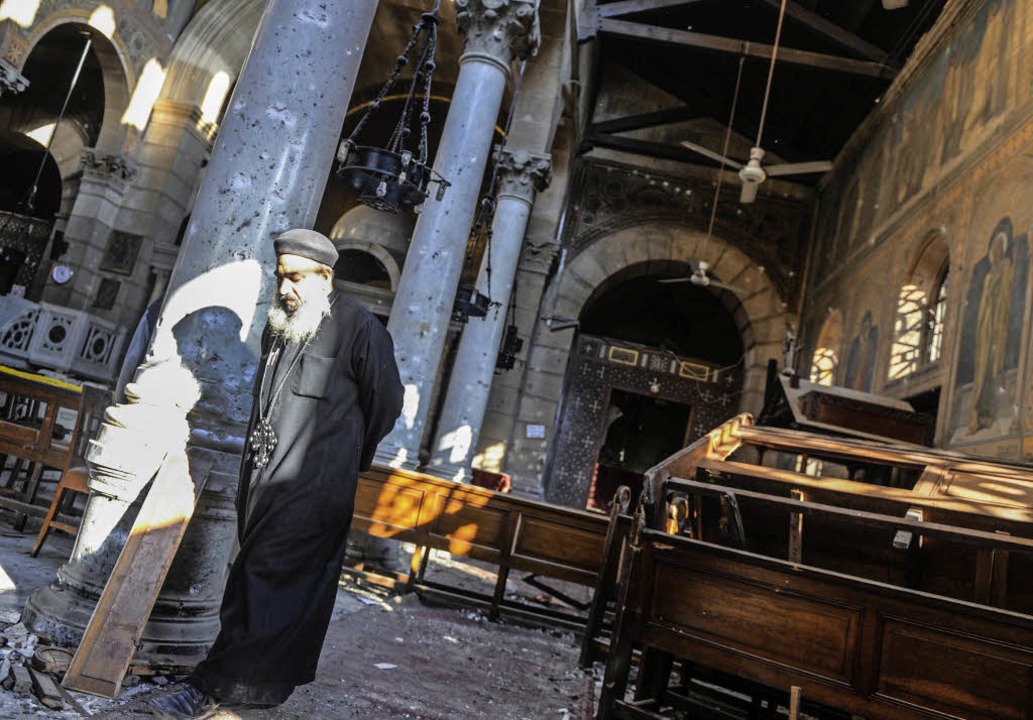 Ein koptischer Priester betrachtet die...n der Kirche  St. Peter und St. Paul.   | Foto: DPA