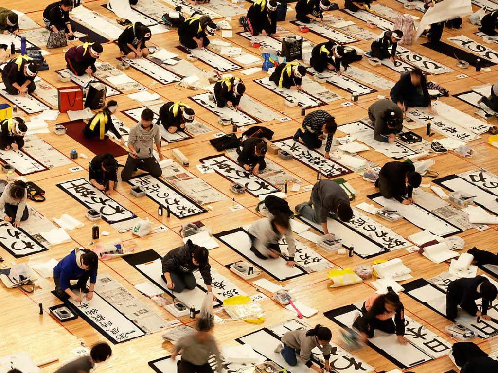 Rund 3000 Teilnehmer tragen mit schwarzer Tusche kunstvoll japanische Schriftzeichen auf weie Papierbahnen auf.
