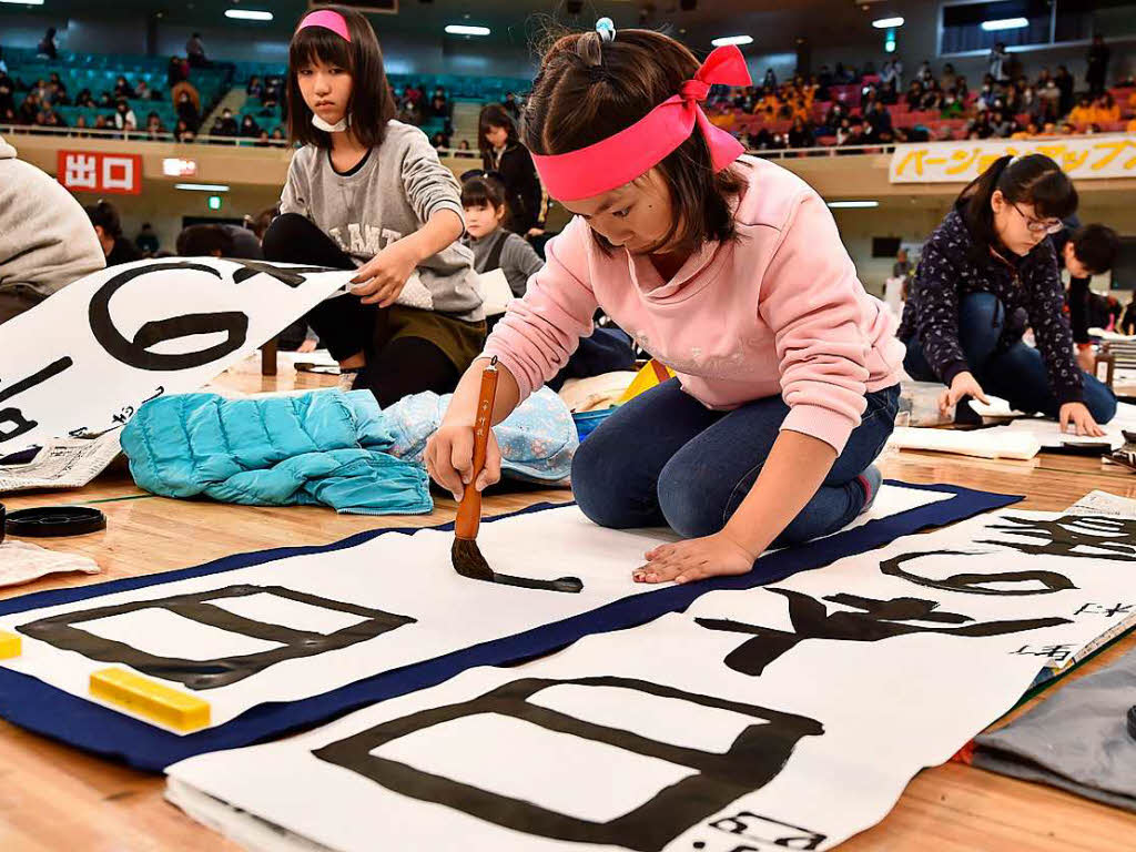 Rund 3000 Teilnehmer tragen mit schwarzer Tusche kunstvoll japanische Schriftzeichen auf weie Papierbahnen auf.