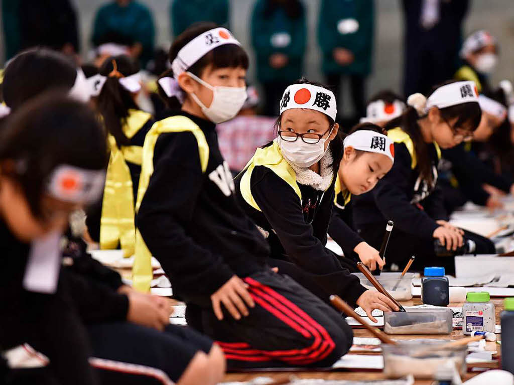 Rund 3000 Teilnehmer tragen mit schwarzer Tusche kunstvoll japanische Schriftzeichen auf weie Papierbahnen auf.