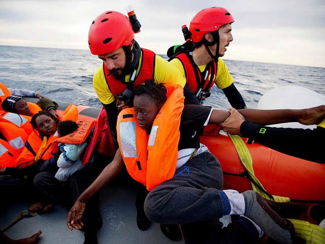Helfer   retten Flchtlinge im Mittelmeer nahe Libyen aus einem Schlauchboot.   | Foto: DPA