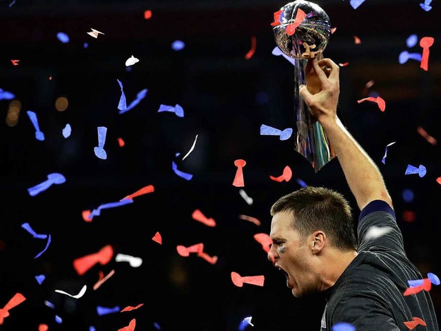 Tom Brady jubelt nach dem Sieg seiner New England Patriots mit dem Pokal.  | Foto: dpa