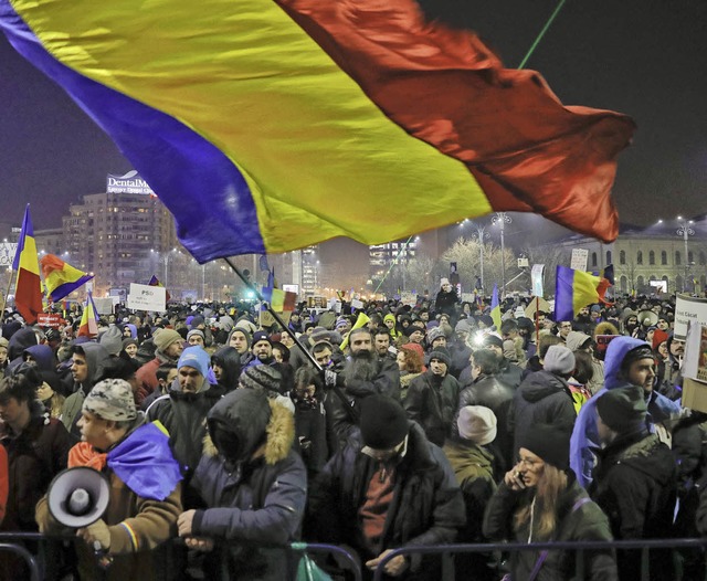 Die Demonstranten schwenken die rumnische Flagge.   | Foto: DPA