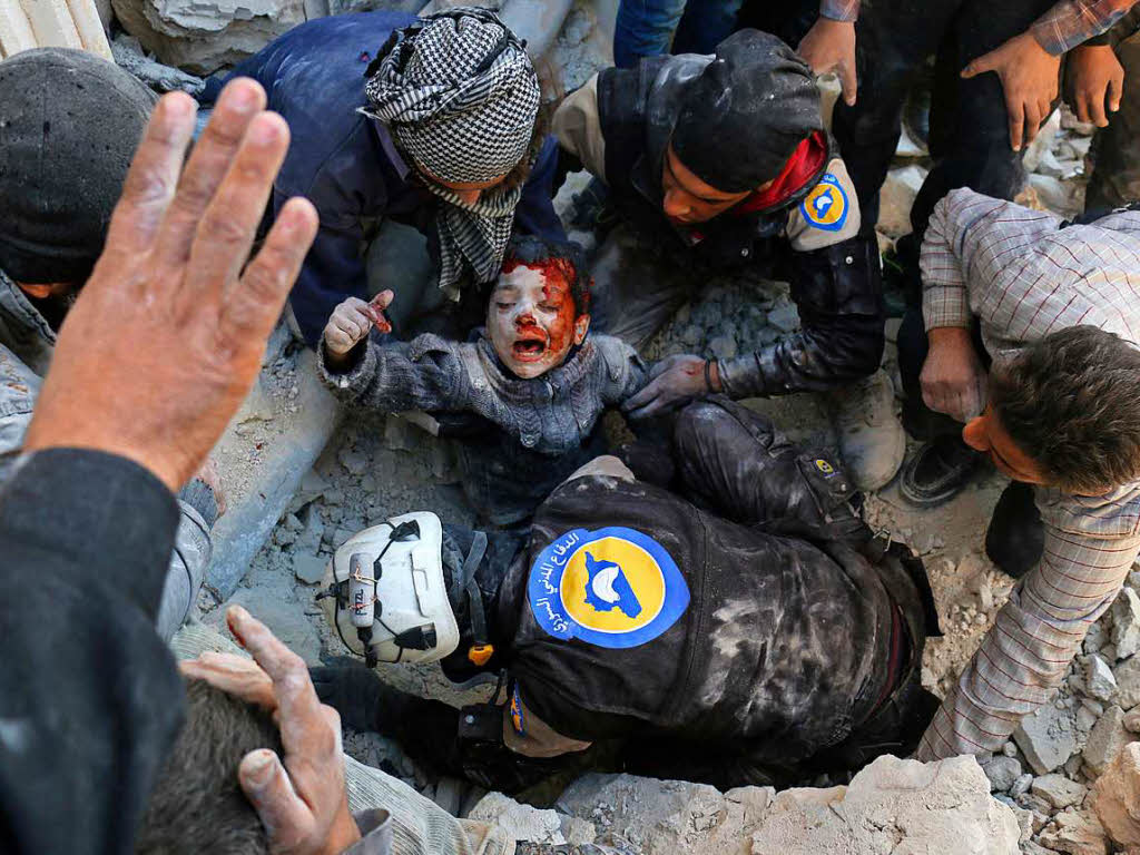 Syrische Zivilhelfer retten einen Jungen, der am 24. November 2016 in Aleppo (Syrien) aus einem nach einem Angriff mit einer Fassbombe (laut Berichten) zusammengestrzten Haus gerettet wird.  Das Bild von Ameer Alhalbi (AFP) wird mit dem zweiten Preis in der Kategorie Spot News, Einzelbild, ausgezeichnet.
