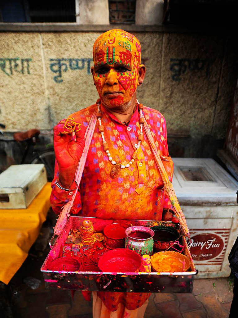 Miit buntem Farbpulver bedeckt wartet ein Teilnehmer  im Bankey Bihari Tempel in Vrindavan (Indien) beim religisen Holi-Fest darauf den Teilnehmern einen Farbstempel aufzudrcken.