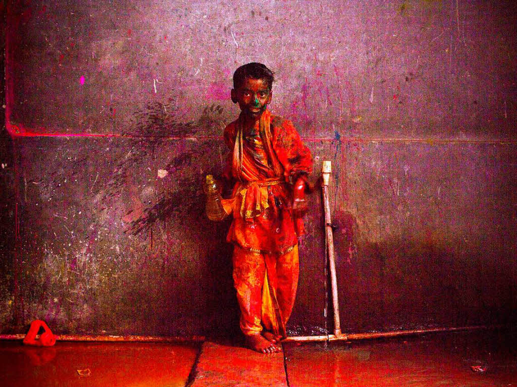 Ein mit Farbe beschmierter Junge steht  in Mathura, Indien.