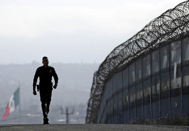 Ein amerikanischer Grenzsoldat geht am Grenzzaun bei San Diego entlang.   | Foto: dpa