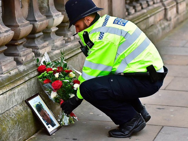 Ein Polizist legt Blumen nieder.  | Foto: dpa