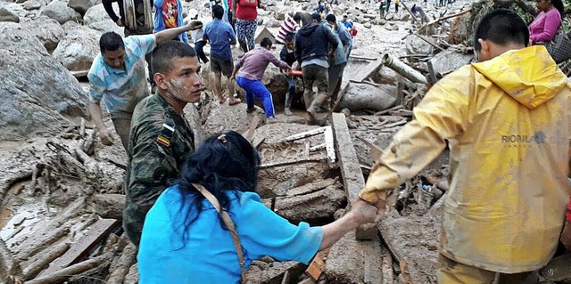 Helfer suchen in den Matschmassen nach berlebenden.  | Foto: dpa