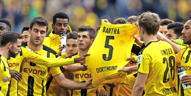 Die Dortmunder Spieler halten nach dem... verletzten Marc Bartra  in die Hhe.   | Foto: dpa