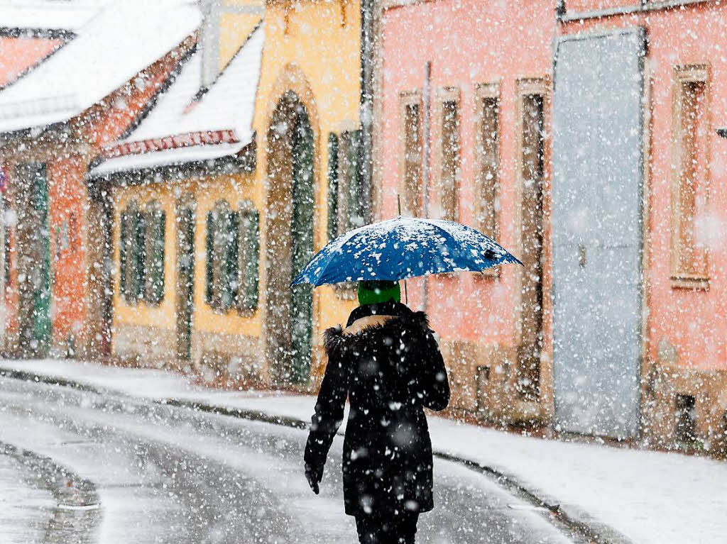 Eine Frau  geht am Montag in Bamberg (Bayern) bei starkem Schneefall ber eine Strae.
