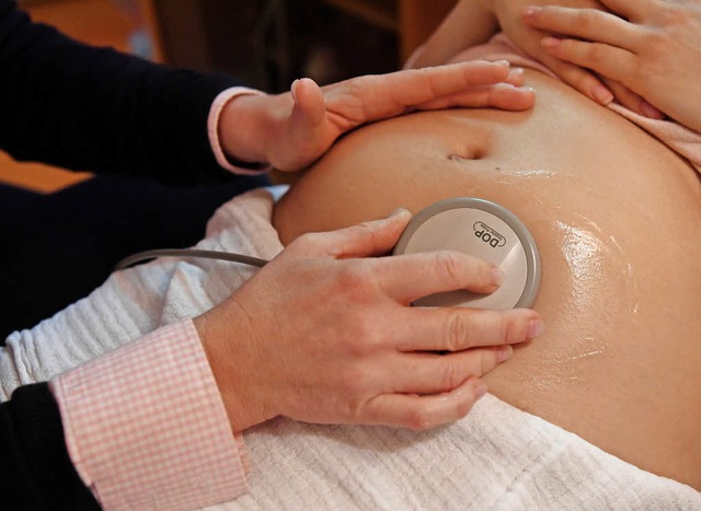 Eine Hebamme hrt den Bauch einer schwangeren Frau ab.   | Foto: dpa