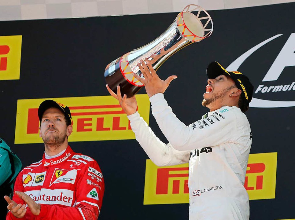 Ausgelassenes Spielen mit der Siegertrophäe: Lewis Hamilton  | Foto: dpa