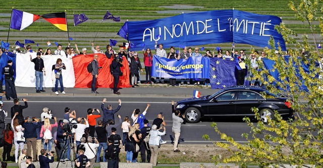 Passanten begren Emmanuel Macron bei seiner Fahrt zum Kanzleramt in Berlin  | Foto: afp