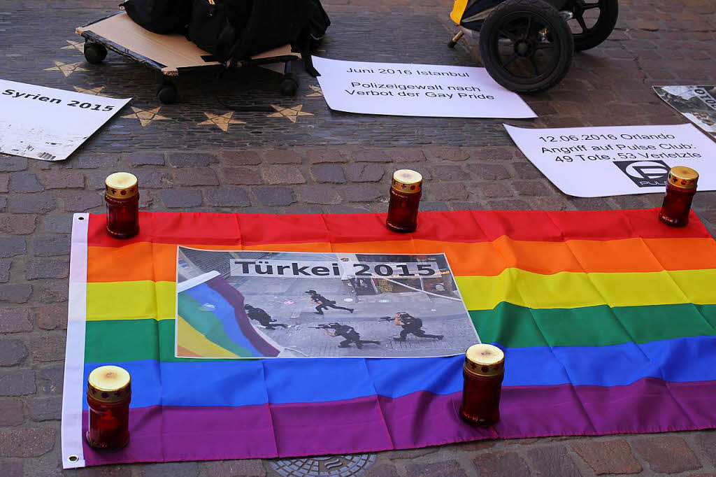 Grabkerzen und Regenbogenfarben. Mit Bildern und Schweigen machen Demonstranten auf Gewalt gegen Homosexuelle und Transgender aufmerksam.
