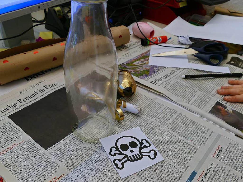 Nun kannst du entweder einen Totenkopf ausdrucken oder ihn natrlich selbst malen. Danach klebst du den Totenkopf mit Klebeband an die Flasche.