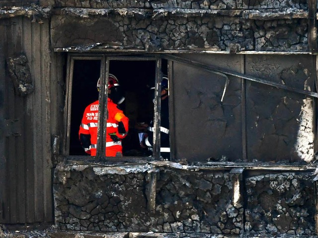 Ein Feuerwehrmann in der ausgebrannten Ruine des Hochhauses.  | Foto: AFP