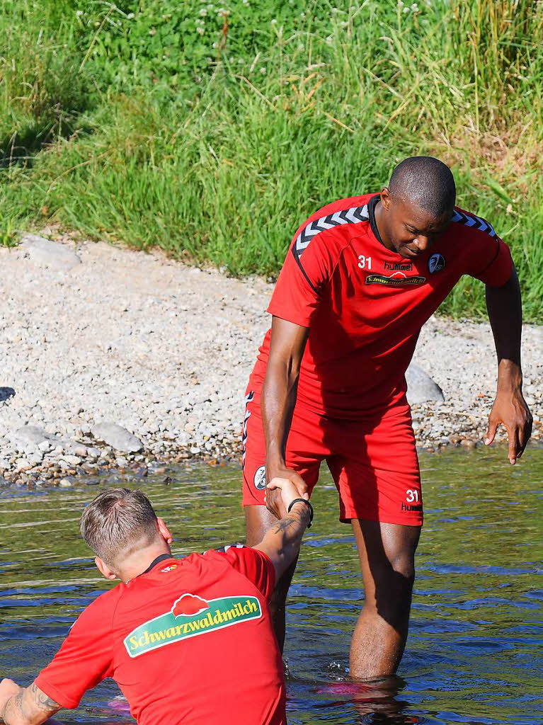 Die Spieler des SC Freiburg entspannen sich beim Bad in der Dreisam.