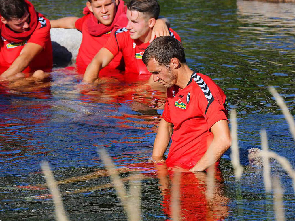 Die Spieler des SC Freiburg entspannen sich beim Bad in der Dreisam.