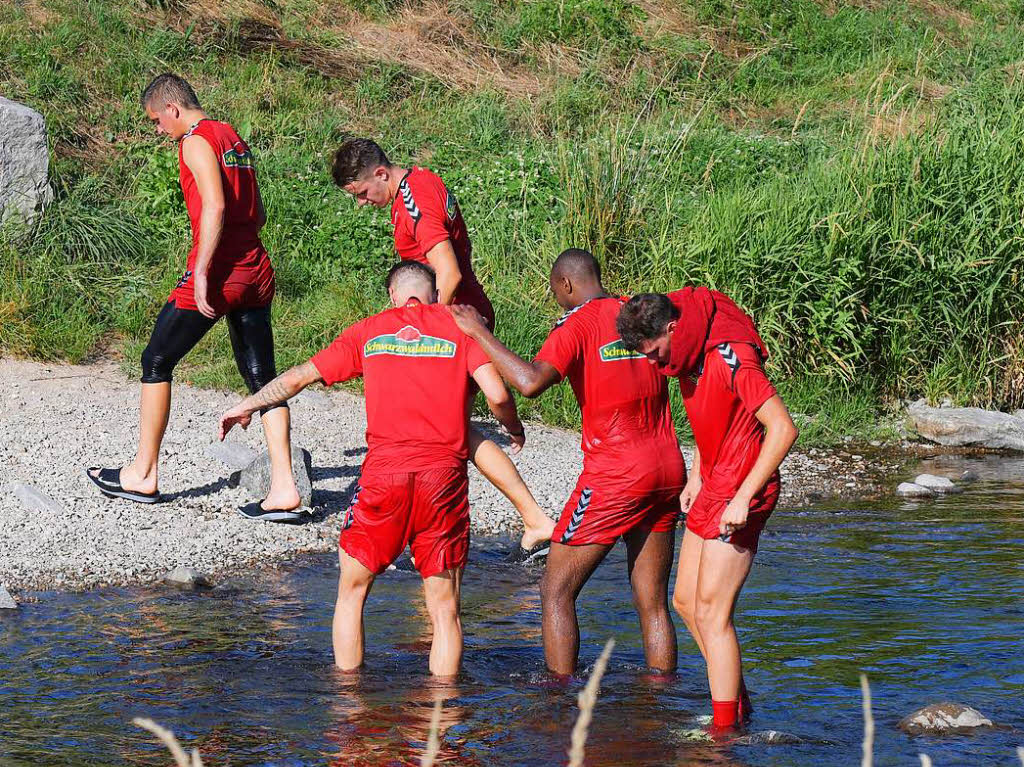 Die Spieler des SC Freiburg entspannen sich beim Bad in der Dreisam.