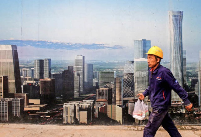 Ein Bauarbeiter in Peking luft vor einem Plakat mit baulichen Visionen vorbei.  | Foto: dpa