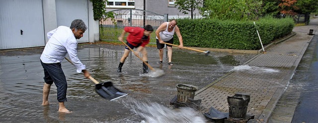 Anwohner schippen Wasser einer berflu... zu den Ablaufschchten in der Strae.  | Foto: Manfred Frietsch