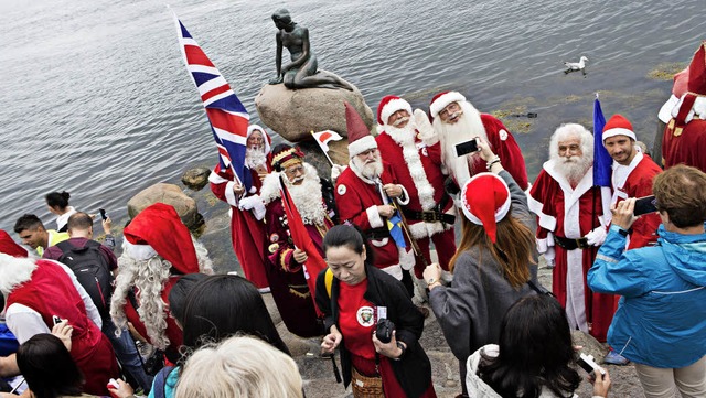 Weihnachtsmnner kommen vor der bronze...ngfrau im Hafen Kopenhagens zusammen.   | Foto: dpa