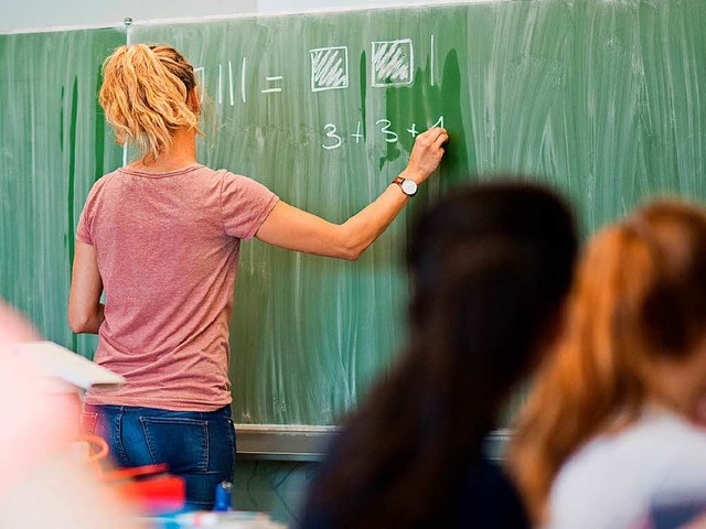 Eine Lehrerin schreibt im Mathematikunterricht an die Schultafel.  | Foto: dpa