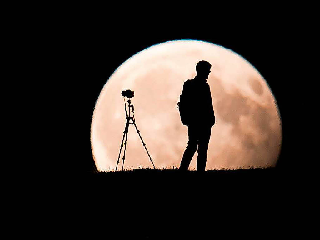 Ein Mann fotografiert in Mnchen den Mond.