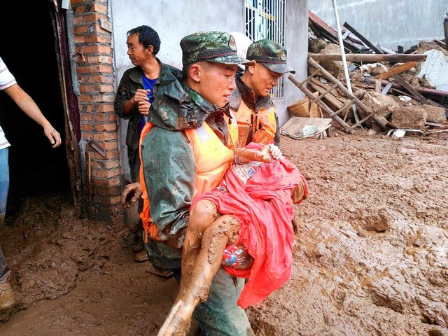 Rettungskrfte tragen einen berlebend...n der Provinz Sichuan aus seinem Haus.  | Foto: AFP