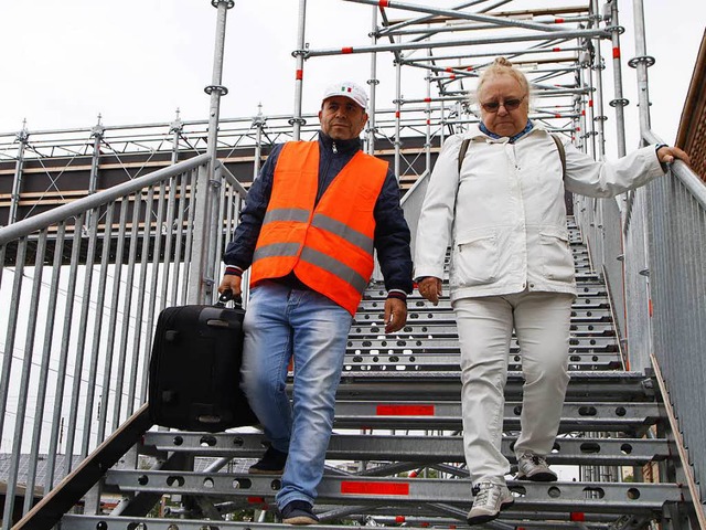 Ein Helfer trgt den Koffer einer Frau ber die Brcke.  | Foto: Heidi Foessel