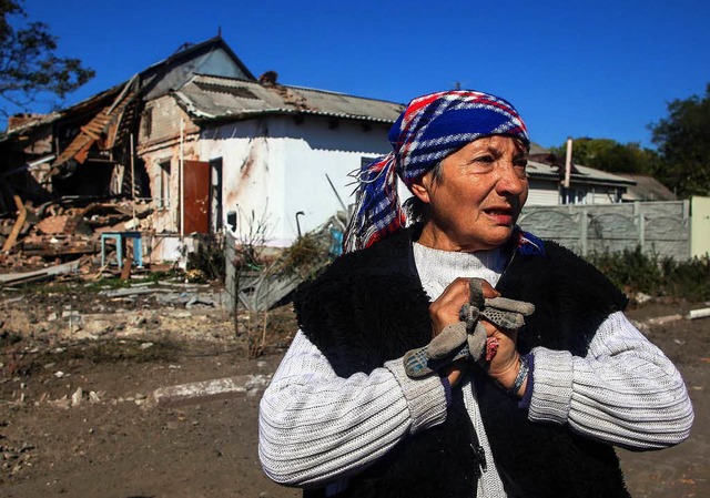 Eine Frau aus Donezk steht vor ihrem zerstrten Haus.   | Foto: dpa