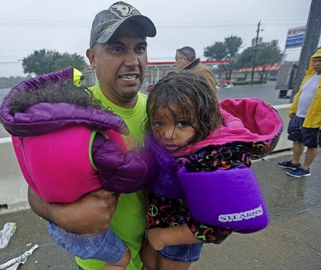 Ein Mann flieht mit seinen Kindern aus den berfluteten Gebieten.   | Foto: dpa