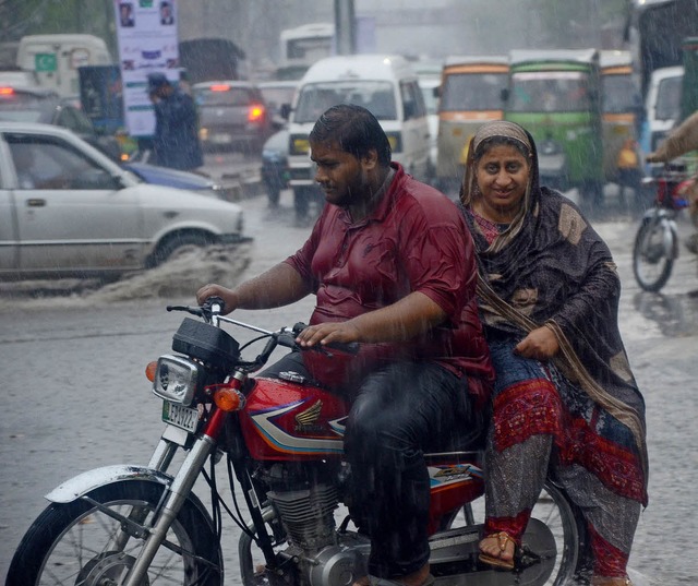 Ein Paar fhrt ber eine berflutete Strae in Lahore, Pakistan.   | Foto: dpa