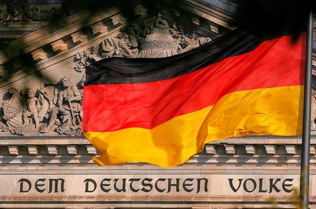 Die Deutschland-Fahne weht vor dem Rei...m deutschen Volke&#8220; zu lesen ist.  | Foto: dpa
